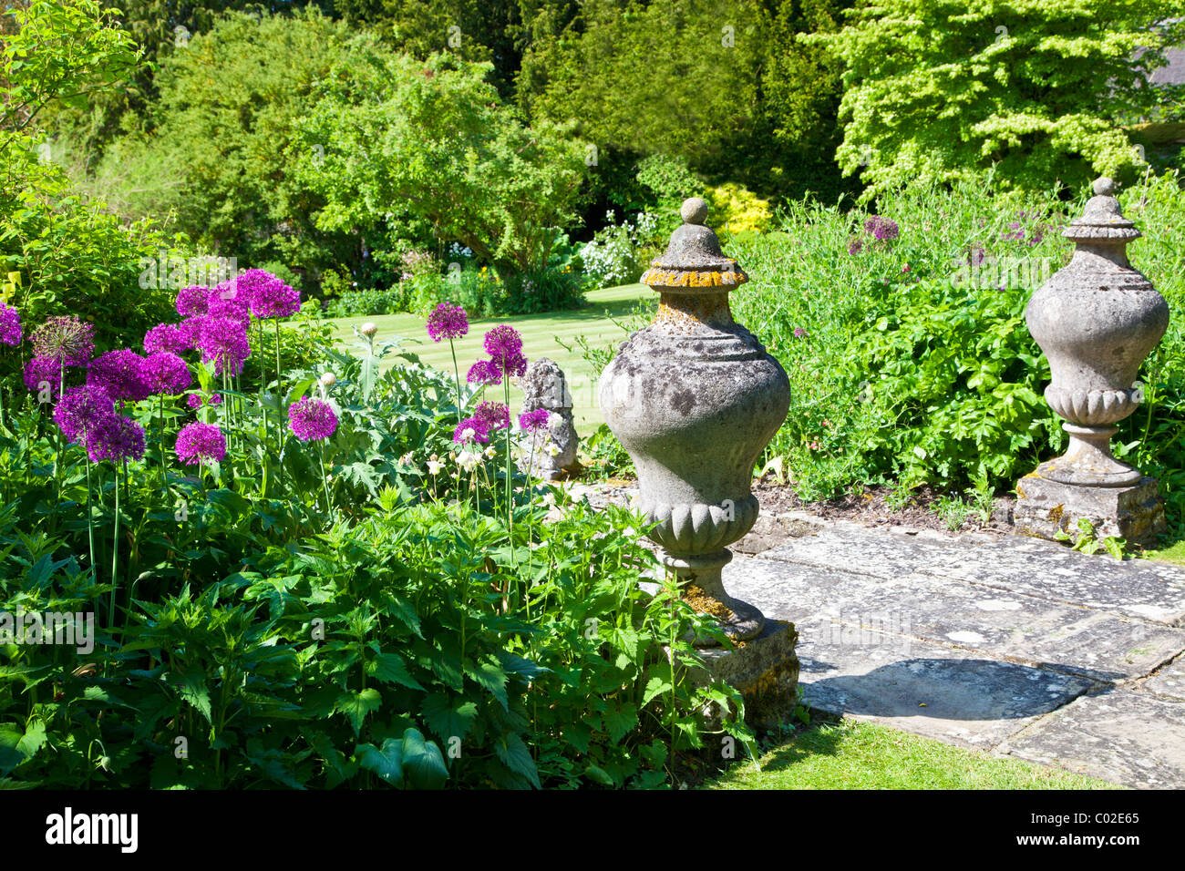 stone garden ornaments and purple allium or onion flowers